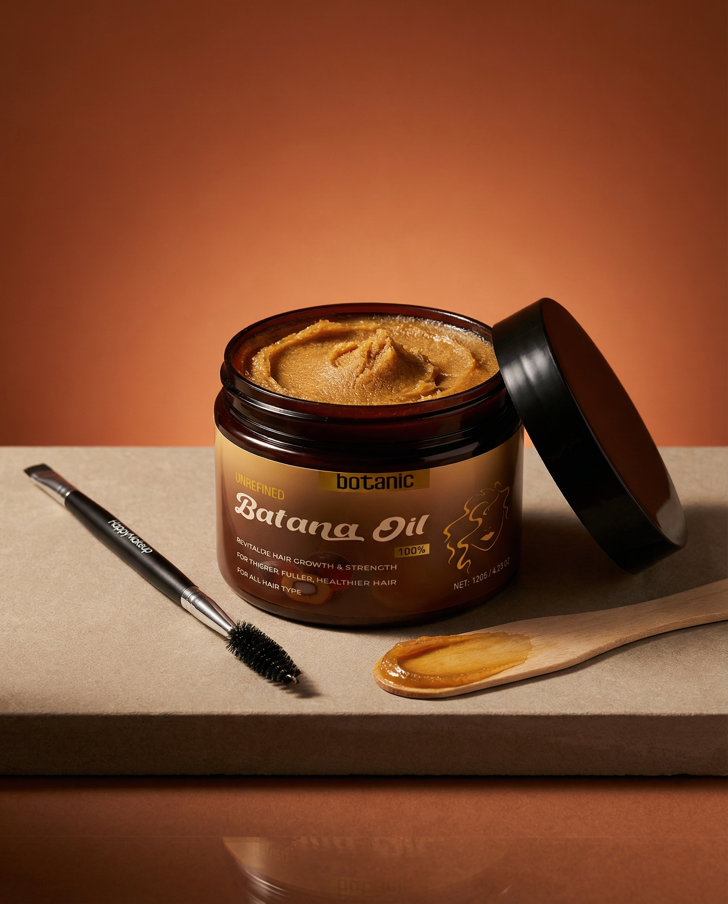 Jar of Batana Oil with a brush and spoonful of oil on a brown background