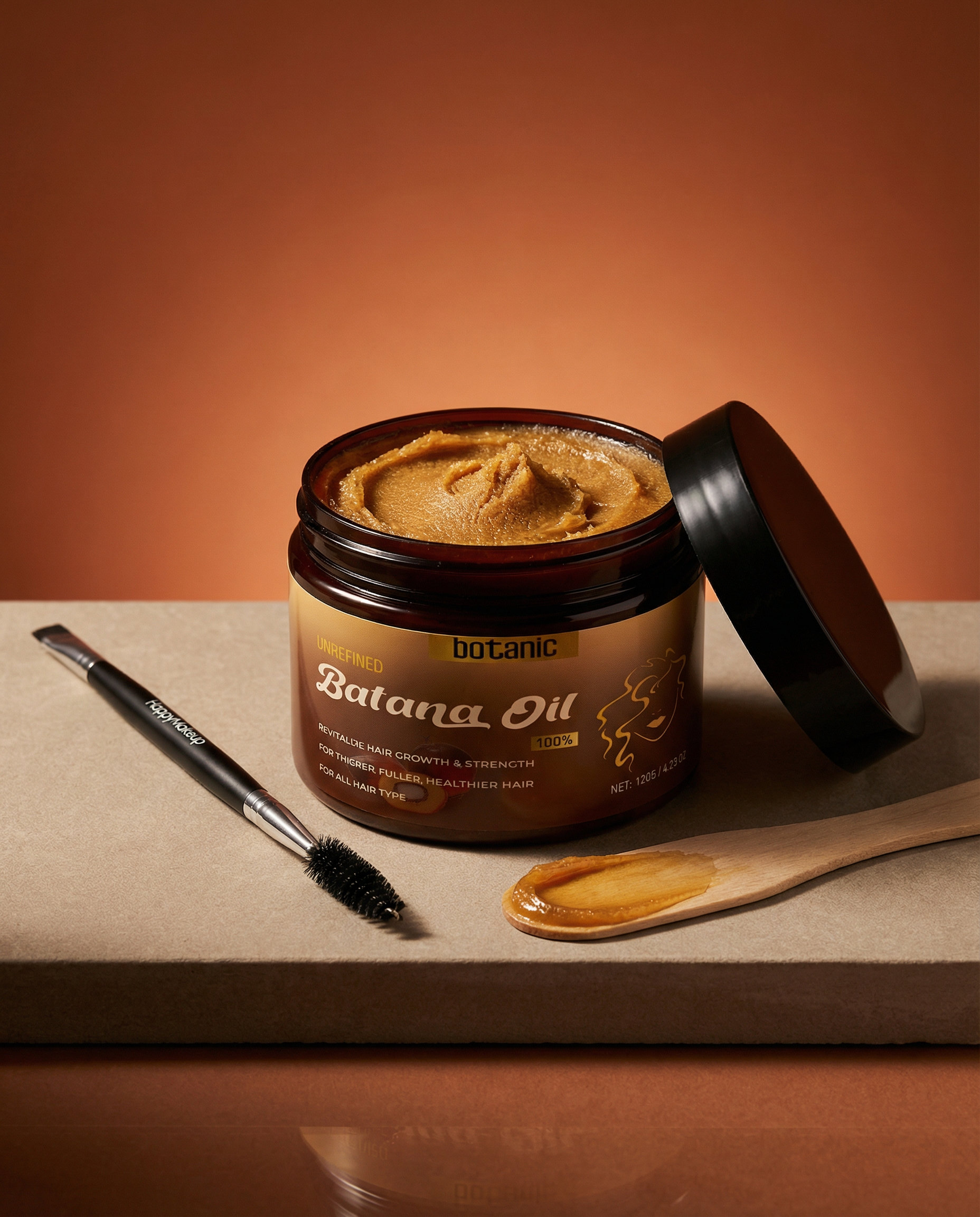 Jar of Batana Oil with a brush and spoonful of oil on a brown background